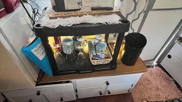Eine kleine Küchenzeile mit einer Kaffeemaschine, einem Wasserkocher und einer Tasse auf der Arbeitsfläche.
