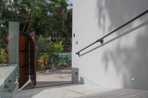 A modern building entrance with a glass door, a pool, and a metal handrail.