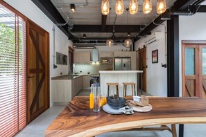 Eine moderne Küche mit Holzschränken, einer Kochinsel und Pendelleuchten.