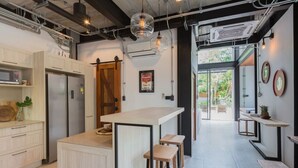 Cocina moderna con una isla central, taburetes de bar y vistas al exterior.