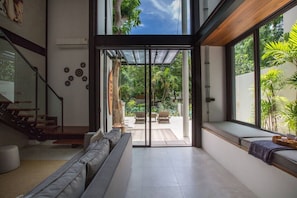 A modern interior with a staircase, a seating area, and a large glass door leading to an outdoor space.
