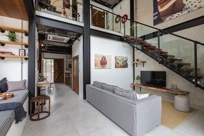 Ein modernes Interieur mit einer Treppe, einem Sofa, einem Essbereich und Kunstwerken an den Wänden.