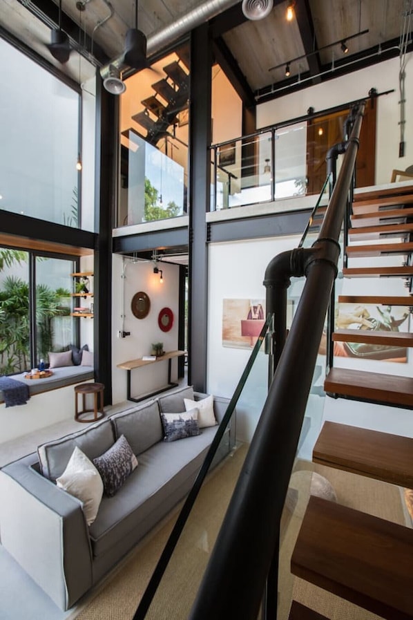 A modern interior with a staircase, a sofa, and a dining area.