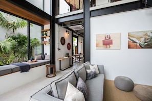 A modern interior with a sofa, a dining area, and artwork on the walls.