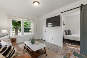 A living room with a sofa, coffee table, and a TV mounted on the wall.