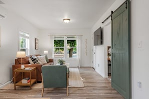 Una sala de estar con un sofá, un sillón, una mesa de centro y una televisión.