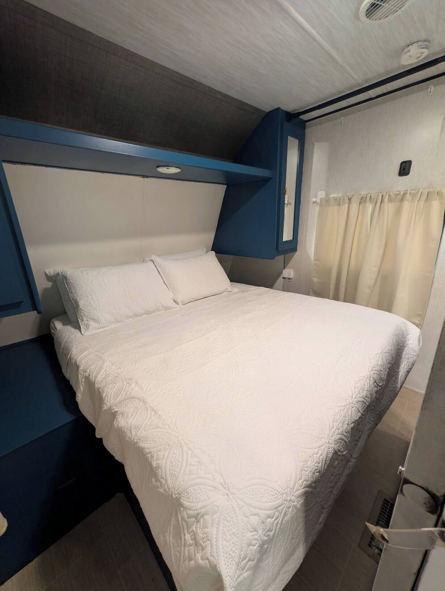 Un lit simple avec une couette blanche, dans une pièce dont la tête de lit est bleue et le mur est blanc.