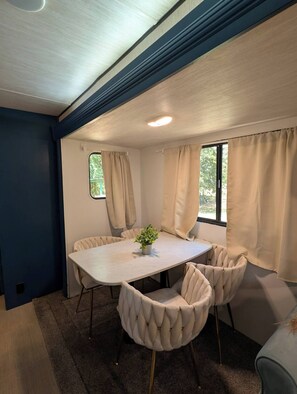 A room with a round table, beige chairs, a potted plant, and curtains. - Brazos Bliss Retreat - River Escape (Weatherford)