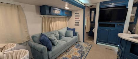 A compact living space with a sofa, a patterned rug, and a kitchenette area.