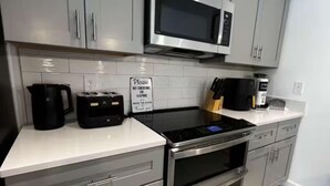 A modern kitchen with grey cabinets, a stainless steel microwave, a coffee maker, and a sign prohibiting smoking or vaping. - Spacious 5-bedroom house in charming Kissimmee with AC (Kissimmee)