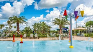 A pool area with water features, lounge chairs, and palm trees. - Spacious 5-bedroom house in charming Kissimmee with AC (Kissimmee)