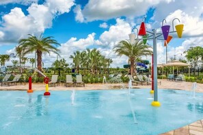 A pool area with water features, lounge chairs, and palm trees. - Spacious 5-bedroom house in charming Kissimmee with AC (Kissimmee)