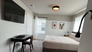 A bedroom with a bed, a desk, a chair, and a bedside table. - Spacious 5-bedroom house in charming Kissimmee with AC (Kissimmee)