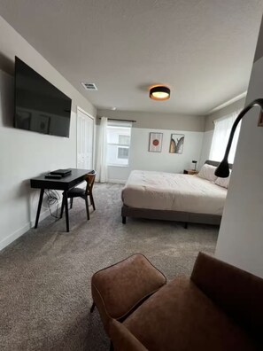 A bedroom with a bed, a desk, a chair, and a bedside table. - Spacious 5-bedroom house in charming Kissimmee with AC (Kissimmee)