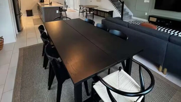 A modern living room with a dark wooden dining table, black chairs, and a large grey sectional sofa. There are two hanging pendant lights with a woven design. - Spacious 5-bedroom house in charming Kissimmee with AC (Kissimmee)