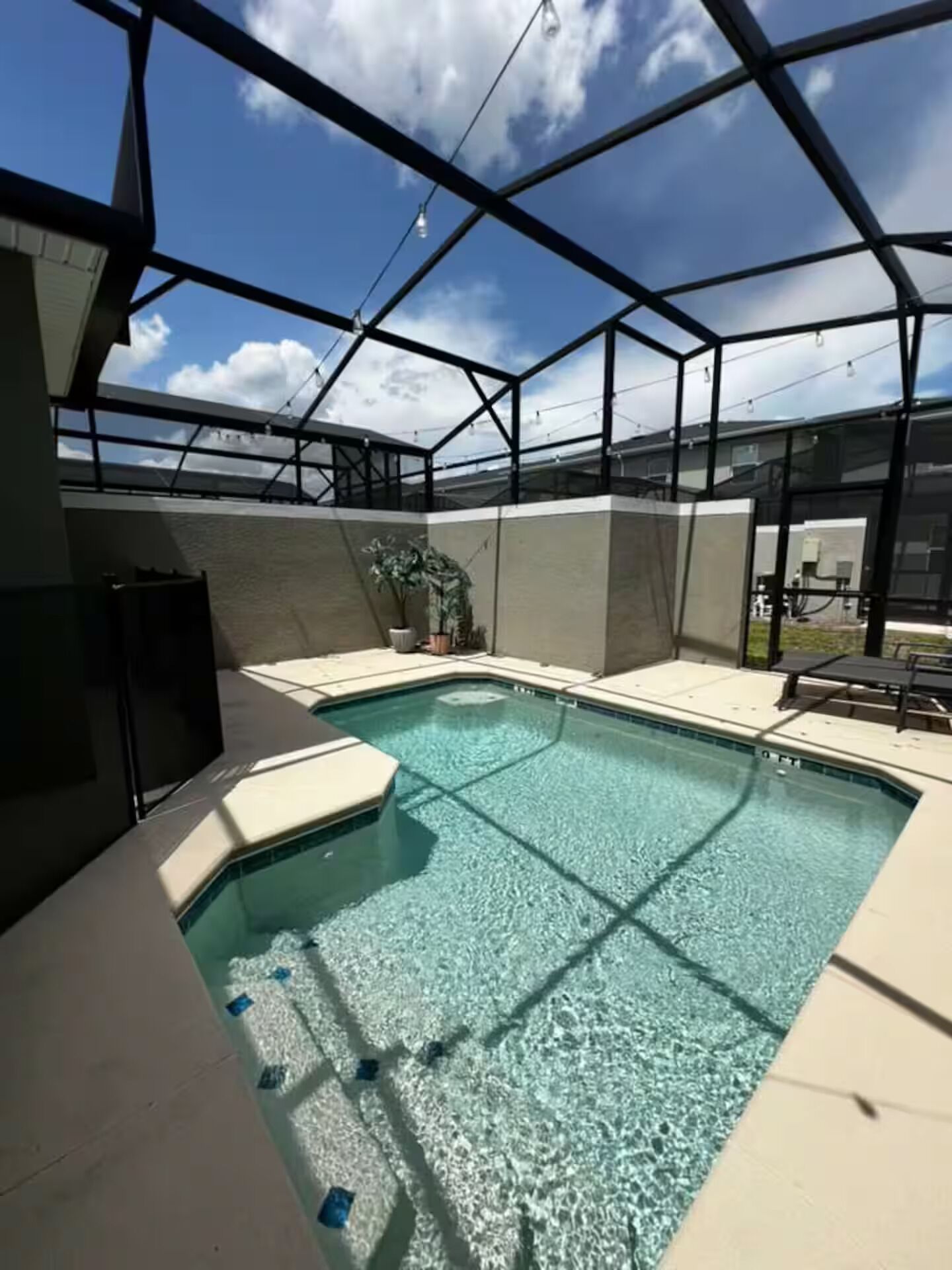 An indoor swimming pool with a clear blue water, surrounded by a glass enclosure and a metal frame structure.
