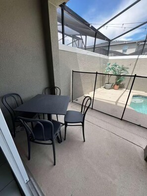 A balcony with a table and chairs, a pool, and a view of a building. - Spacious 5-bedroom house in charming Kissimmee with AC (Kissimmee)