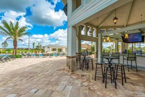 A covered outdoor area with a pool, bar, and seating. - Spacious 5-bedroom house in charming Kissimmee with AC (Kissimmee)