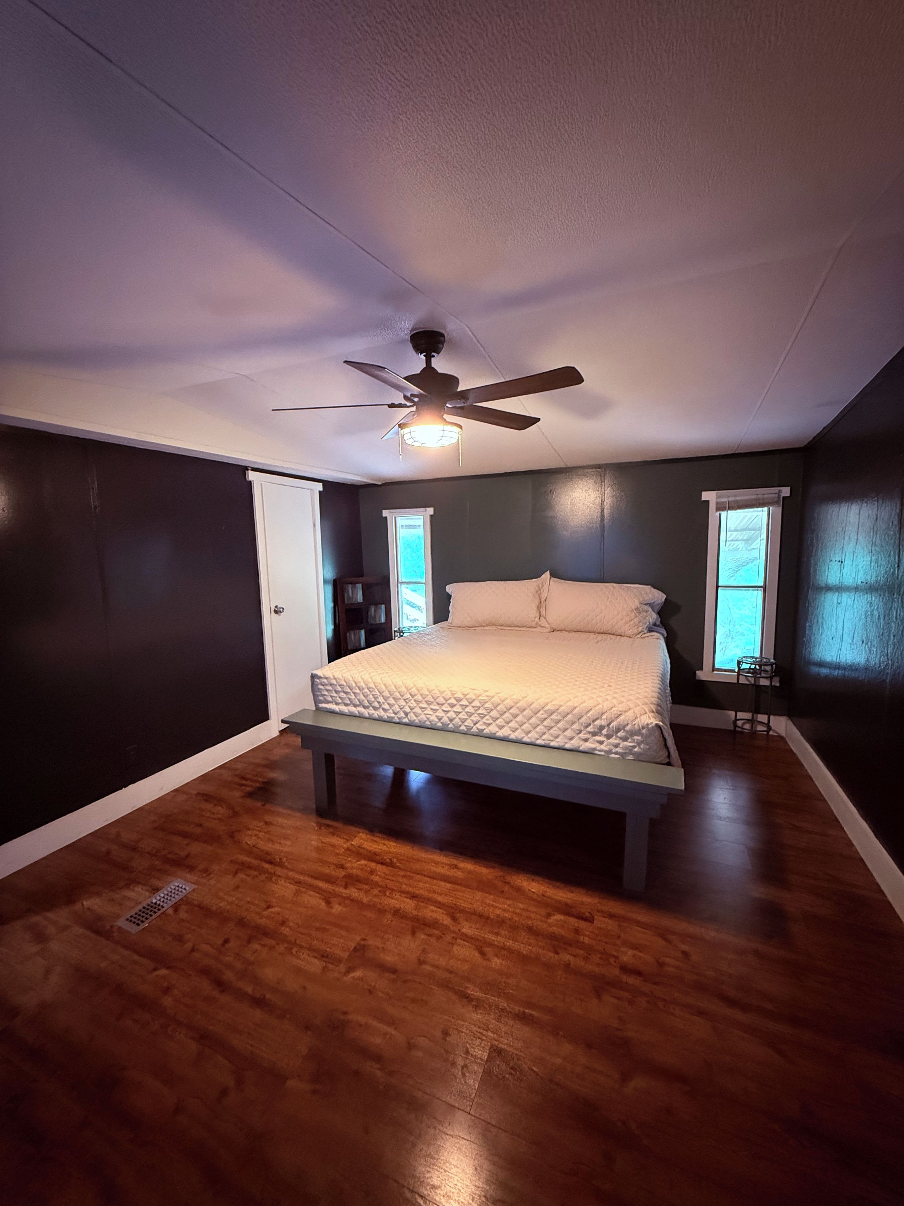 Un dormitorio con cama, ventilador de techo y ventana.