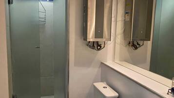 Uma casa de banho moderna com cabine de duche em vidro, sanita branca e lavatório com espelho em cima.