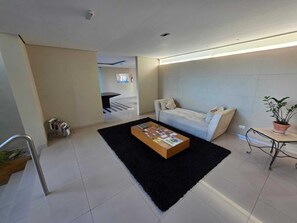 A modern living room with a black rug, a wooden coffee table, a white sofa, and a small table with a plant. - Duplex Apartment: Style and comfort just a few meters from Berrini & Shopping (São Paulo)