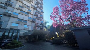 A modern building with multiple balconies and a large tree with pink flowers. - Duplex Apartment: Style and comfort just a few meters from Berrini & Shopping (São Paulo)