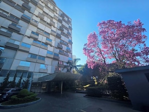 A modern building with multiple balconies and a large tree with pink flowers. - Duplex Apartment: Style and comfort just a few meters from Berrini & Shopping (São Paulo)