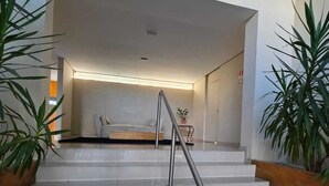 A staircase with a metal handrail leading to a room with a bed and a bedside table. - Duplex Apartment: Style and comfort just a few meters from Berrini & Shopping (São Paulo)