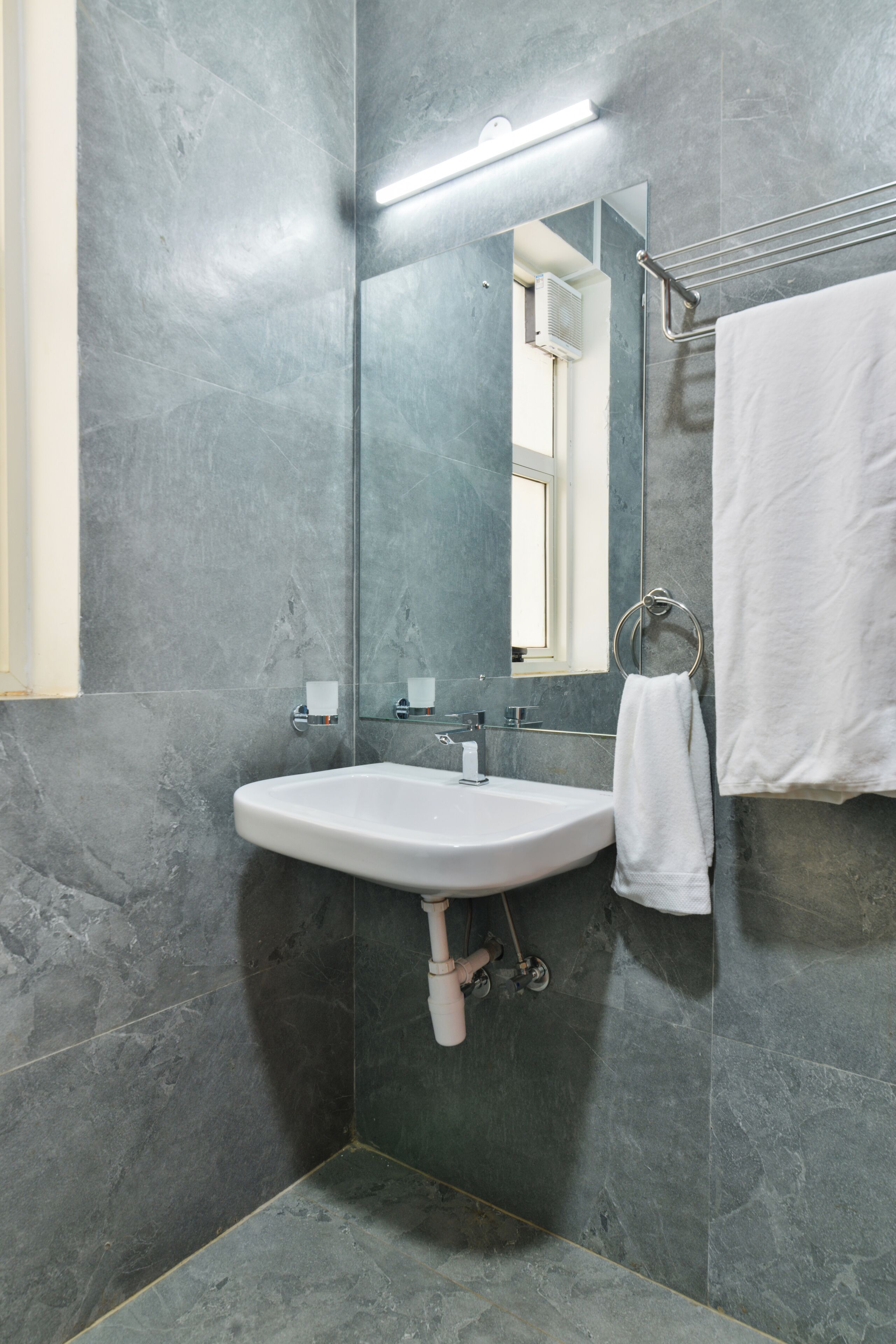 A bathroom with a white sink, a mirror, and a towel rack.