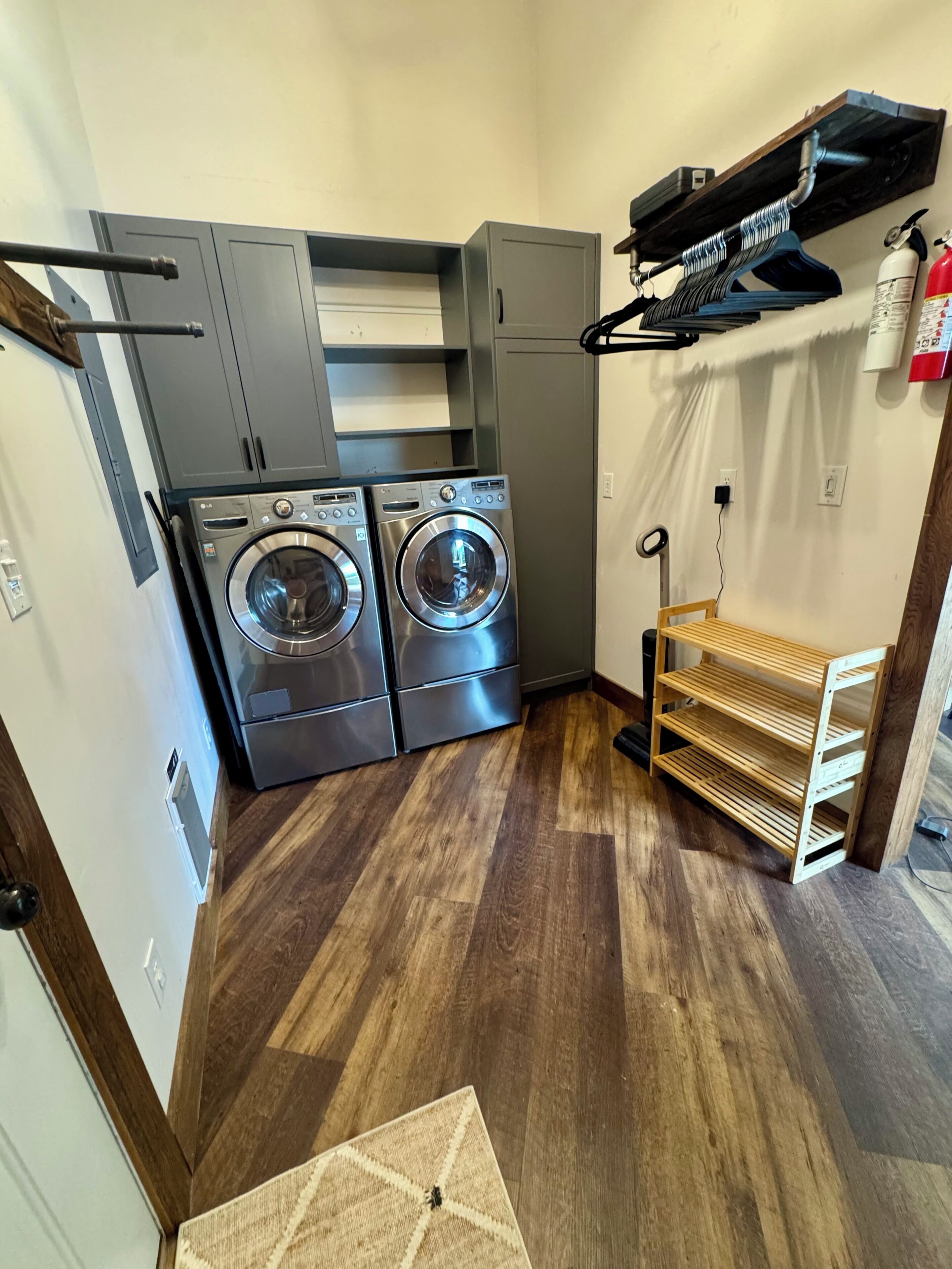 A laundry room with two front-loading washers, a drying rack, and a fire extinguisher.