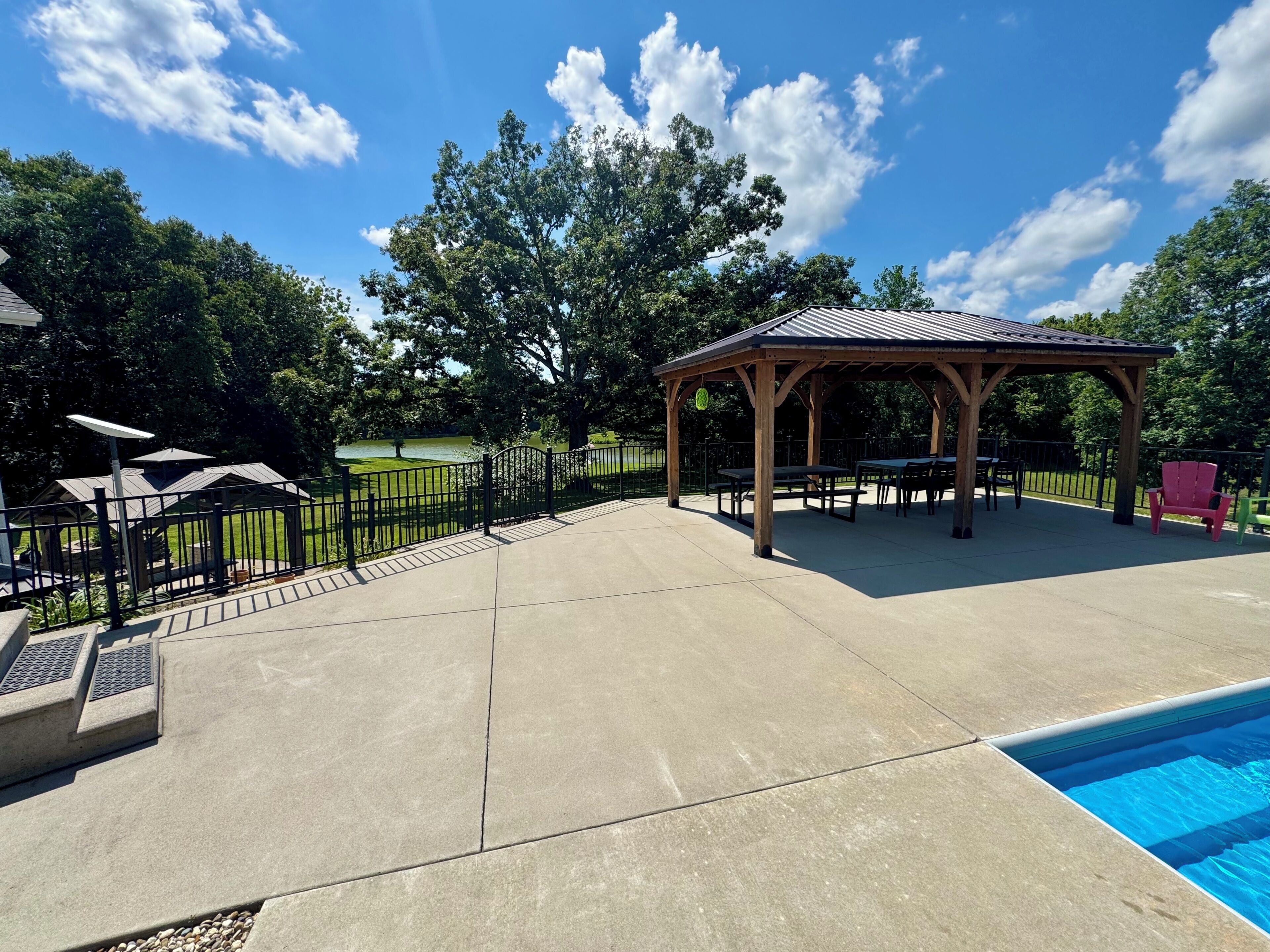A covered outdoor area with a pool, picnic tables, and a gazebo.