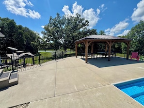 A covered outdoor area with a pool, picnic tables, and a gazebo.