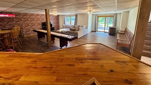 A spacious living area with a wooden floor, a brick wall, and a seating area with a sofa and chairs.