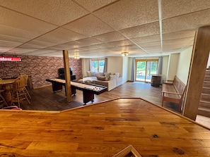 A spacious living area with a wooden floor, a brick wall, and a seating area with a sofa and chairs.