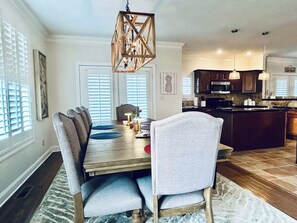 A dining area with a wooden table, grey upholstered chairs, and a chandelier. - Panoramic Views of KY Lake.  (Buchanan)