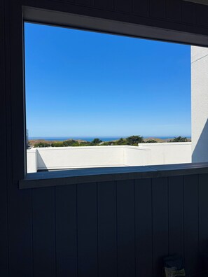 A window with a clear view of a white building and a blue sky. - Ocean View Luxury Condo off Monterey Bay Brand New (Marina)