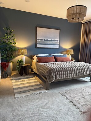 A bedroom with a bed, two bedside lamps, a large potted plant, a framed picture on the wall, and a window with curtains. - Ocean View Luxury Condo off Monterey Bay Brand New (Marina)