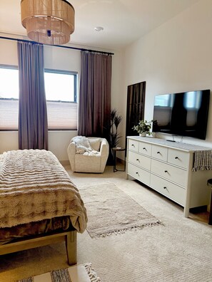 A bedroom with a bed, a chair, a dresser, a television, and a window with curtains. - Ocean View Luxury Condo off Monterey Bay Brand New (Marina)