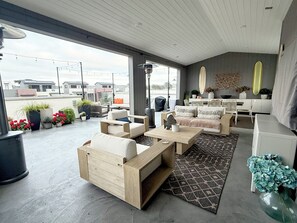 Un espacio exterior moderno para disfrutar, con sofá, mesa de centro y comedor, que ofrece vistas de la ciudad.