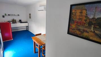 A room with a blue floor, a wooden table, a red cabinet, and a wall-mounted air conditioner.