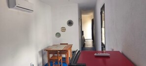 Una habitación con una mesa de comedor, sillas, una mesa roja y un control remoto.