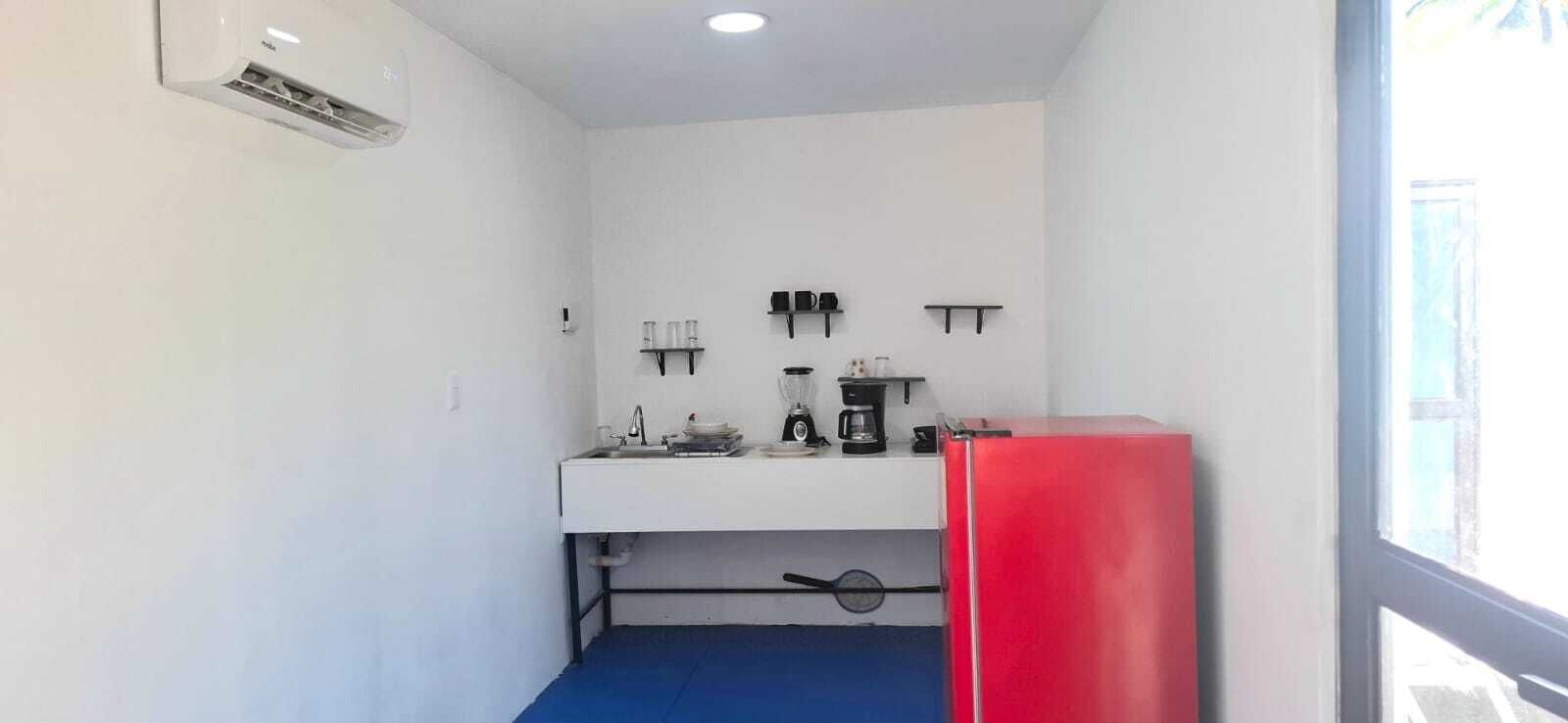 Una piccola cucina accessoriata con lavandino, macchina da caffè e frigorifero rosso.