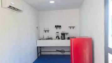 Una piccola cucina accessoriata con lavandino, macchina da caffè e frigorifero rosso.