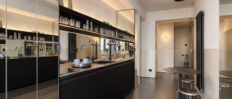 A modern kitchen with a central island, mirrored backsplash, and a dining area with a round table and stools.