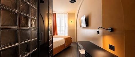 A hotel room with a bed, a desk, a TV mounted on the wall, and a sliding glass door.