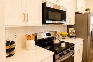 A modern kitchen with white cabinets, stainless steel appliances, and a bowl of lemons on the counter. - Talk of TownHome! (Indian Springs Village)