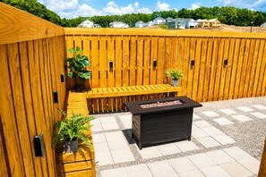 A wooden fence, a bench, a planter with a plant, and a fire pit. - Talk of TownHome! (Indian Springs Village)