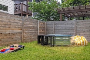 A backyard with a wooden fence, a metal hot tub, a small table, and a bean bag chair. - Rainey St Retreat / Cowboy Pool & Urban Chic (Austin)