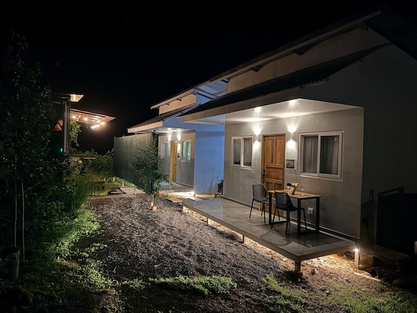 A modern house with a covered patio, outdoor seating, and a well-lit entrance.