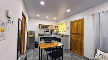 Una cocina compacta con comedor, refrigerador, pileta y puerta de madera.